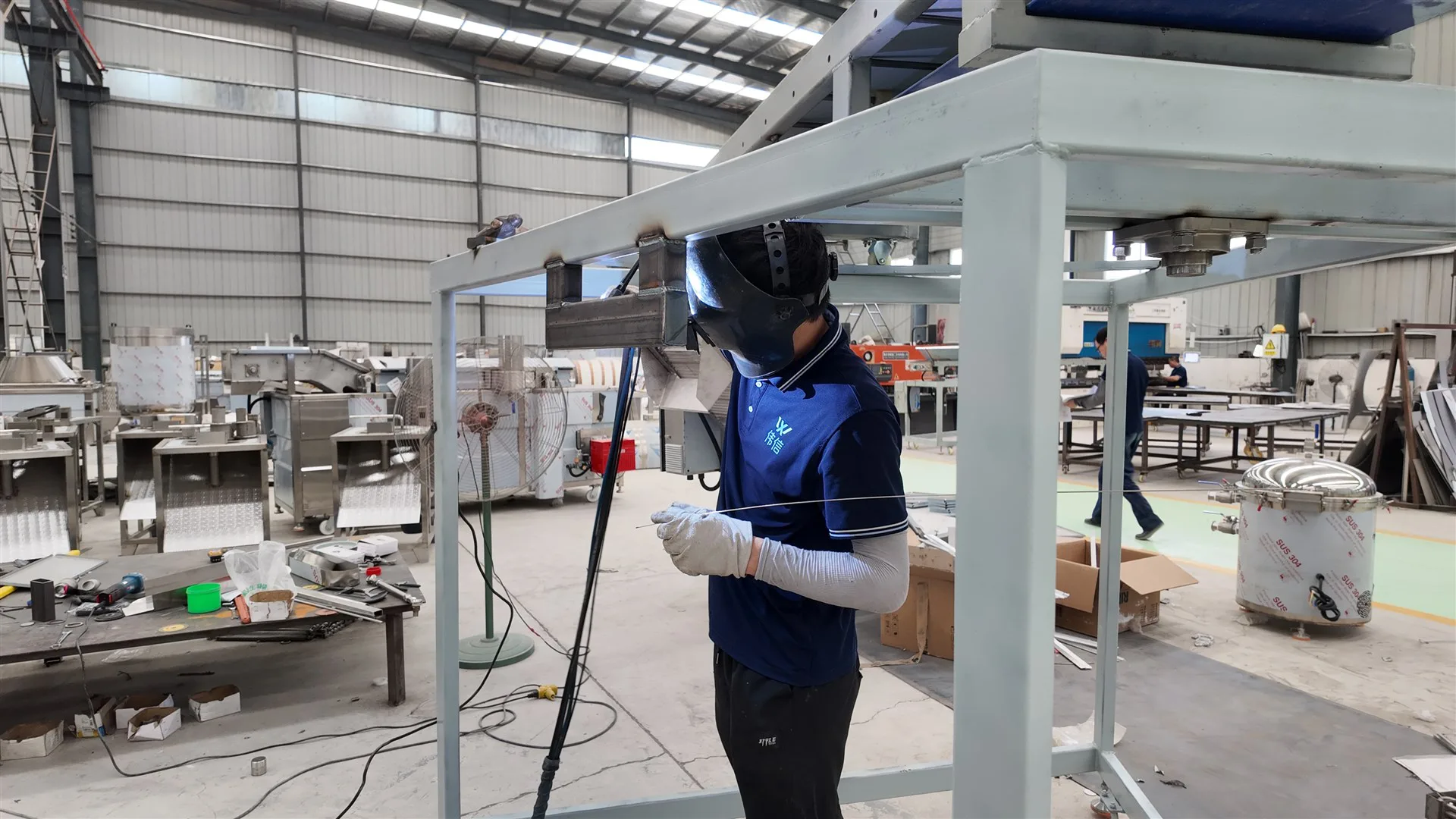 Technician welding a stainless steel food processing machine