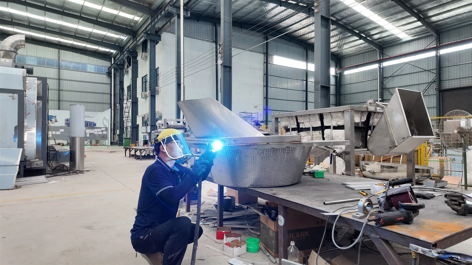 Technician welding food processing equipment in the SHEPODY workshop